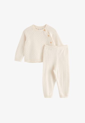 Maglioncino per neonato color crema lavorato a maglia con tre bottoni di legno sulla spalla, abbinato a pantaloni in maglia coordinati.
