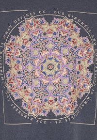 Camiseta de color marino con un patrón de mandala colorido que incluye elementos florales en tonos azules, rojos y dorados. El texto alrededor del diseño incluye frases inspiradoras.