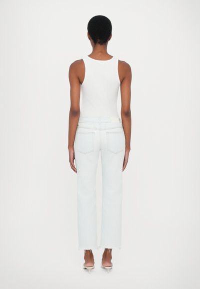 Top blanco sin mangas, jeans de talle alto en un azul claro con un dobladillo deshilachado, diseño minimalista y sin patrones visibles. Vista trasera del atuendo.