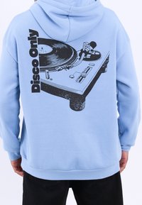 Felpa con cappuccio azzurro chiaro con una grafica di un giradischi sul retro e la scritta "Disco Only" in nero. Realizzata in misto cotone, vestibilità comoda.