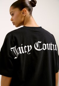 Mustast puuvillast kvaliteetne luksuslik naiste t-särk, mille tagaküljel on suur valge kiri "Juicy Couture". Pehme tekstuuriga, lõõgastavas lõikes.