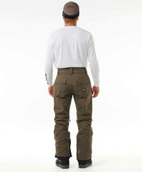 Pantalons de neige marron avec une coupe décontractée, dotés de poches arrière, de zips aux chevilles et d'un patch logo. Portés avec une chemise blanche à manches longues.