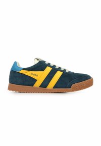 Zapatilla de ante azul marino con franjas laterales amarillas y talón azul. Cintas suaves, suela de goma texturizada marrón y logo "Gola" en el costado.