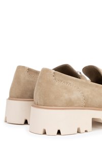 Zapatos de ante beiges con un perfil bajo, que presentan un upper texturizado y una suela de goma ligera y gruesa con acentos cortados.