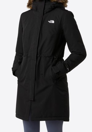 Parka isolante noire avec capuche bordée de fourrure, taille ajustable, poches zippées pour les mains et logo The North Face sur la poitrine.
