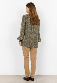 Long-sleeve blouse with a multicolor abstract pattern in shades of green, brown, and beige; paired with khaki pants and black shoes.