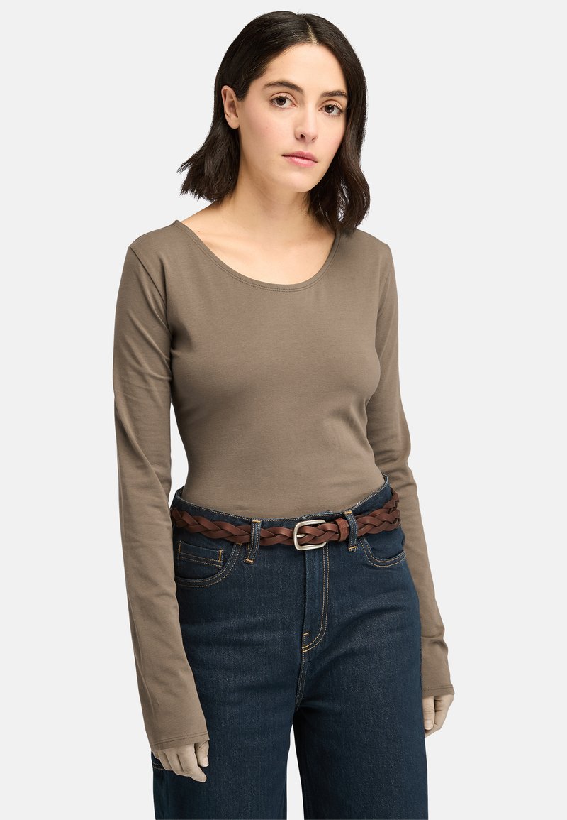 Maglia aderente marrone a maniche lunghe con scollo rotondo, abbinata a jeans scuri a vita alta e una cintura intrecciata marrone.