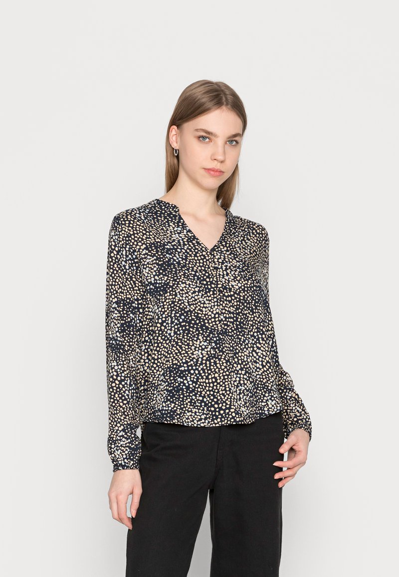 Blusa a maniche lunghe con scollo a V, caratterizzata da una base nera decorata con un motivo astratto crema e blu, realizzata in tessuto leggero.