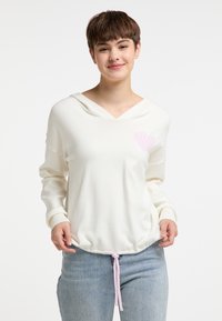 Hoodie in crèmekleur met een roze hartdetail op de borst, voorzien van een trekkoord aan de onderkant en geribbelde manchetten, gemaakt van zachte stof.