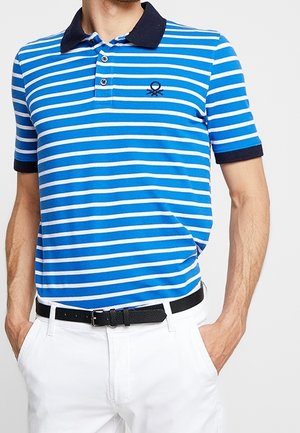 Mann trägt ein blau-weiß gestreiftes Poloshirt mit Marine-Kragen und -Bündchen, kombiniert mit weißen Hosen und einem schwarzen Gürtel.