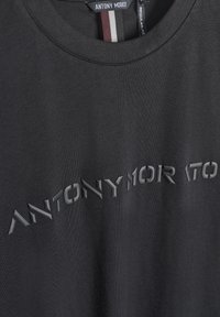 Camiseta negra de tela suave con el texto en relieve "ANTONY MORATO". Tiene un escote redondo y un diseño de corte regular.