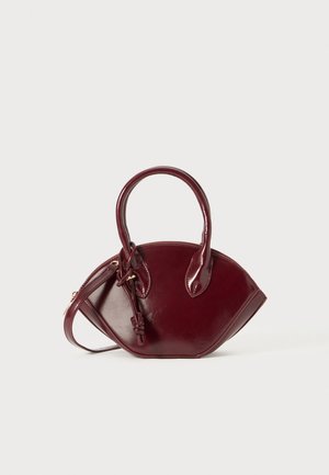 Burgundy leather handbag with a rounded shape, two short handles, zip closure, and knotted detail on the handle. Smooth texture.