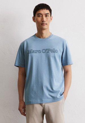 Lichtblauwe katoenen t-shirt met "Marc O'Polo" in contrasterende donkere kleur. Korte mouwen en een klassieke ronde hals.