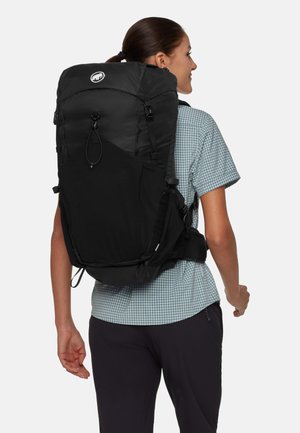 Zaino da trekking nero con un design strutturato, dotato di tasche laterali in rete, spallacci regolabili e un logo circolare sulla parte superiore.