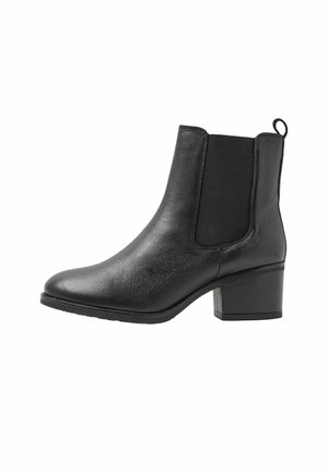 Bottine en cuir noir avec talon bloc, panneaux latéraux élastiques, bout arrondi et languette à l'arrière.