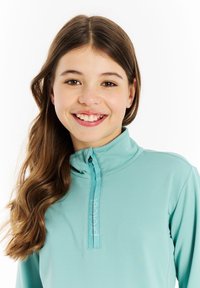 Tyrkysový zipsový top s dlhým rukávom a vysokým golierom, so štítkom na prednej strane a hladkým, mierne textúrovaným materiálom.