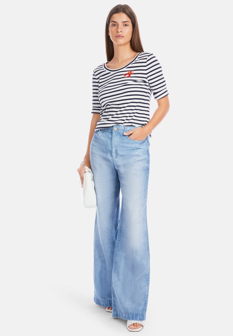Striped short-sleeve top with red lobster embroidery, paired with light blue wide-leg jeans and a small white handbag.