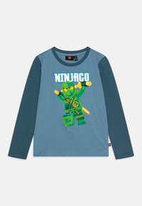 Long-sleeve blue T-shirt with green sleeves, featuring a graphic of a Ninjago character holding weapons and the text "NINJAGO" above.
