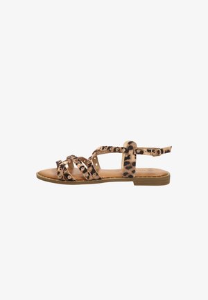 Sandalia plana con tiras de estampado de leopardo que presentan ojetes metálicos circulares y un pequeño cierre de hebilla, sobre una suela marrón claro con tacón bajo.