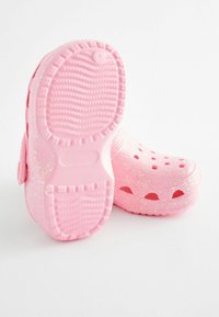Rosa Gummiclogs mit einem glänzenden, funkelnden Finish. Verfügt über belüftete Löcher und eine strukturierte Sohle für besseren Halt. Runde Form mit sanften Kanten.