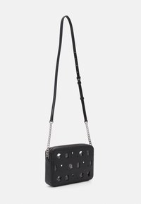 Borsa a tracolla in pelle nera con design a intaglio, tracolla regolabile e dettagli in catena argentata. Chiusura con zip e forma rettangolare piatta.