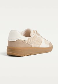 Scarpa atletica beige con tomaia in rete, dettagli in camoscio e pelle, punta arrotondata, suola in gomma e dettagli testurizzati sul tallone.