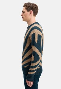 Knitted sweater in teal and beige, featuring a bold striped pattern. Crew neck, ribbed cuffs, and textured fabric for a cozy appearance.