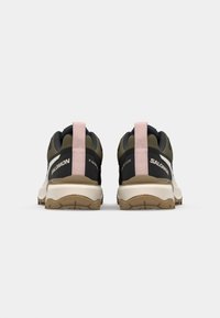 Heather grønne og sorte trail sko med en pink hælflap, struktureret mesh-overdel og gummisål med et mønstret slidbane for greb.