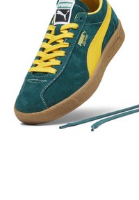 Puma dolphin sneakers in teal suede with yellow laces and accents, featuring a textured gum sole and embroidered logo detail.