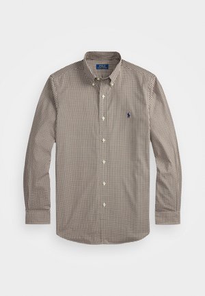 Chemise à manches longues à carreaux marron et blancs avec un col boutonné, featuring un logo brodé bleu sur la poitrine. Matériau en coton.
