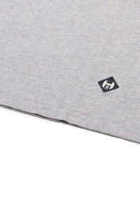 Grå T-shirt med rund halsudskæring, blødt bomuldsstof, foldet kant og et lille sort broderet logo i nederste hjørne.