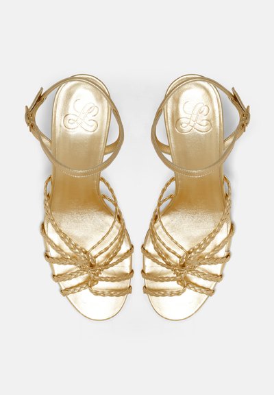 Goldene metallische Sandalen mit geflochtenen Riemen und Schnalle am Knöchel. Die glatte Textur und das offene Zehendesign sorgen für Atmungsaktivität und Stil.