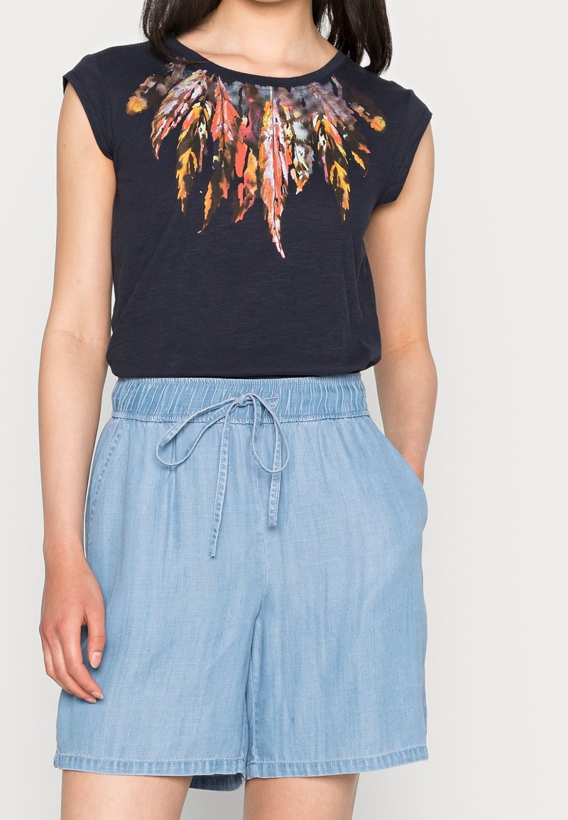 T-shirt marine avec motif de feuilles en orange et rouge, associé à un short à cordon de serrage bleu clair en tissu doux et léger.