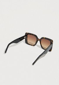 Teknősbéka mintázatú napszemüveg négyzet alakú kerettel, barna árnyalatú lencsékkel és fekete, texturált mintájú szárakkal.