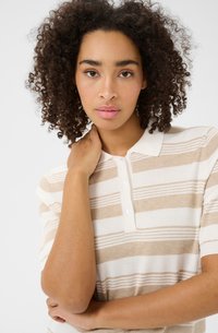 Polo rayé beige et blanc avec un col, des manches courtes et une patte de boutonnage à trois boutons, fabriqué en tissu doux et texturé.