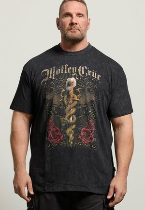 Mann trägt ein schwarzes Mötley Crüe Band-T-Shirt mit einer geflügelten Schlange, die sich um ein Schwert windet, mit roten Rosen auf jeder Seite.