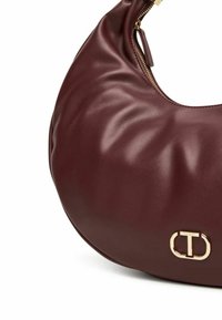 Borsa a mano in pelle marrone con una forma rotonda e morbida, dotata di una cerniera dorata e di un logo in evidenza. Texture liscia con leggere pieghe.