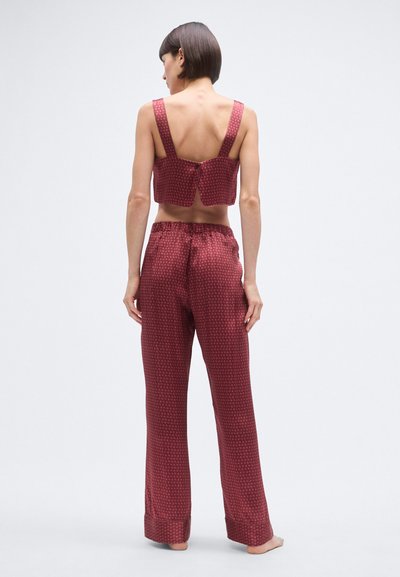 Bordo krāsas mājas apģērbu komplekts ar īsām topu ar platām siksnām un aizdari mugurpusē, kopā ar vaļīgām, rakstainām biksēm.