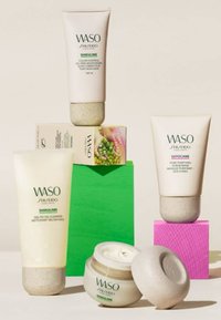 Quatre produits de soin WASO : un nettoyant gel-en-huile et un hydratant de contrôle de couleur dans des tubes beiges, ainsi qu'un gommage masque et une crème dans des contenants ronds.