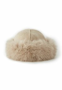 Stickad beige hatt med rund form, med en mjuk, fluffig pälskant. Texturen kontrasterar en slät topp med ett plyschigt, fylligt band.