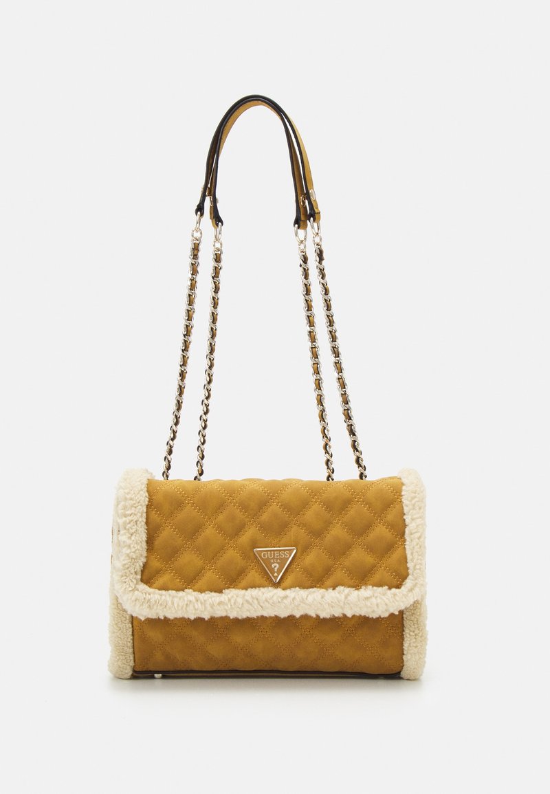 Bruine gewatteerde schoudertas met een crèmekleurige schapenvacht rand, ketting- en leren schouderriem, en een driehoekig Guess-logo op de klep.
