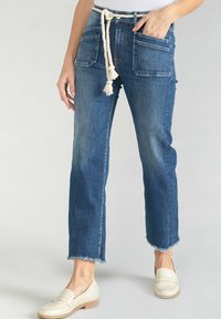 Jean en denim bleu clair avec une coupe décontractée, poches avant et cordon de serrage en rope. Les bords effilochés ajoutent de la texture à la conception longueur cheville.