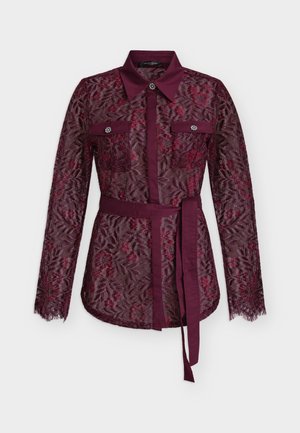 Μπλούζα με μακριά μανίκια σε μπορντό δαντέλα με λουλουδάτο σχέδιο, μυτερό γιακά, εμπρόσθιες τσέπες με λεπτομέρεια κουμπιού και ζώνη μέσης από το ίδιο ύφασμα.