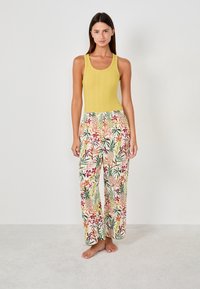 Top in cotone a coste giallo abbinato a pantaloni larghi con fantasia floreale multicolore. Tessuto morbido con vestibilità comoda. Senza hardware visibile.