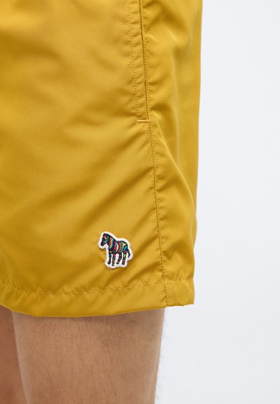 Sárga fürdőnadrág sima felülettel és varrott szegéllyel, bal oldalon színes hímzett zebra motívummal.