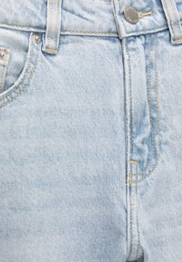 Jeans de mezclilla azul claro con un diseño de cintura alta, botón plateado y costuras amarillas contrastantes a lo largo de las costuras y los bolsillos.