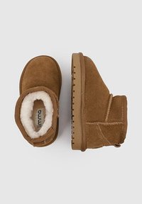 Botas de tobillo de ante marrón con forro de suave pelo sintético, punta redonda y suela de goma texturizada, con detalles cosidos a los lados.