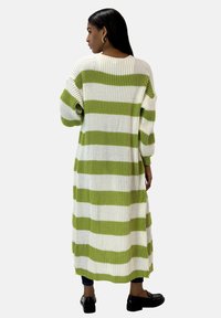 Lång ribbad stickad kofta med växlande gröna och vita ränder. Den har en lös passform, vida ärmar och går neranför knäna.
