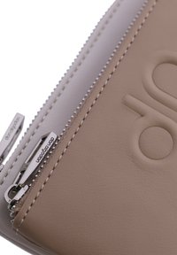 Bolsita de cuero beige claro con una superficie texturizada, presenta un zipper de metal plateado y detalles de costura a lo largo de los bordes.