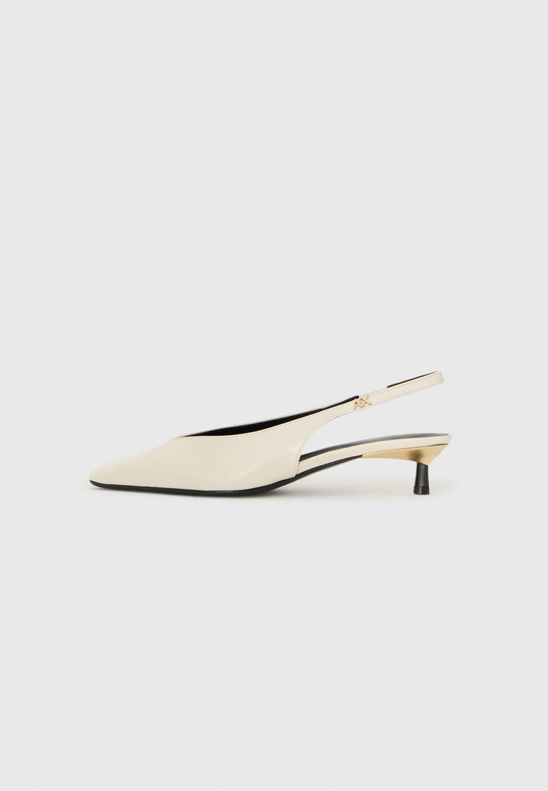 Beidzamā gaiši brūnā lakotas ādas slingback apavi ar smailu purngalu, šauru melnu papēdi un metāliski zelta akcentiem sānos.